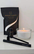 Bougie Blanc pur Maison Charlee allumée avec sable de bougie végétal, parfum de Grasse, briquet USB rechargeable et éteignoir.