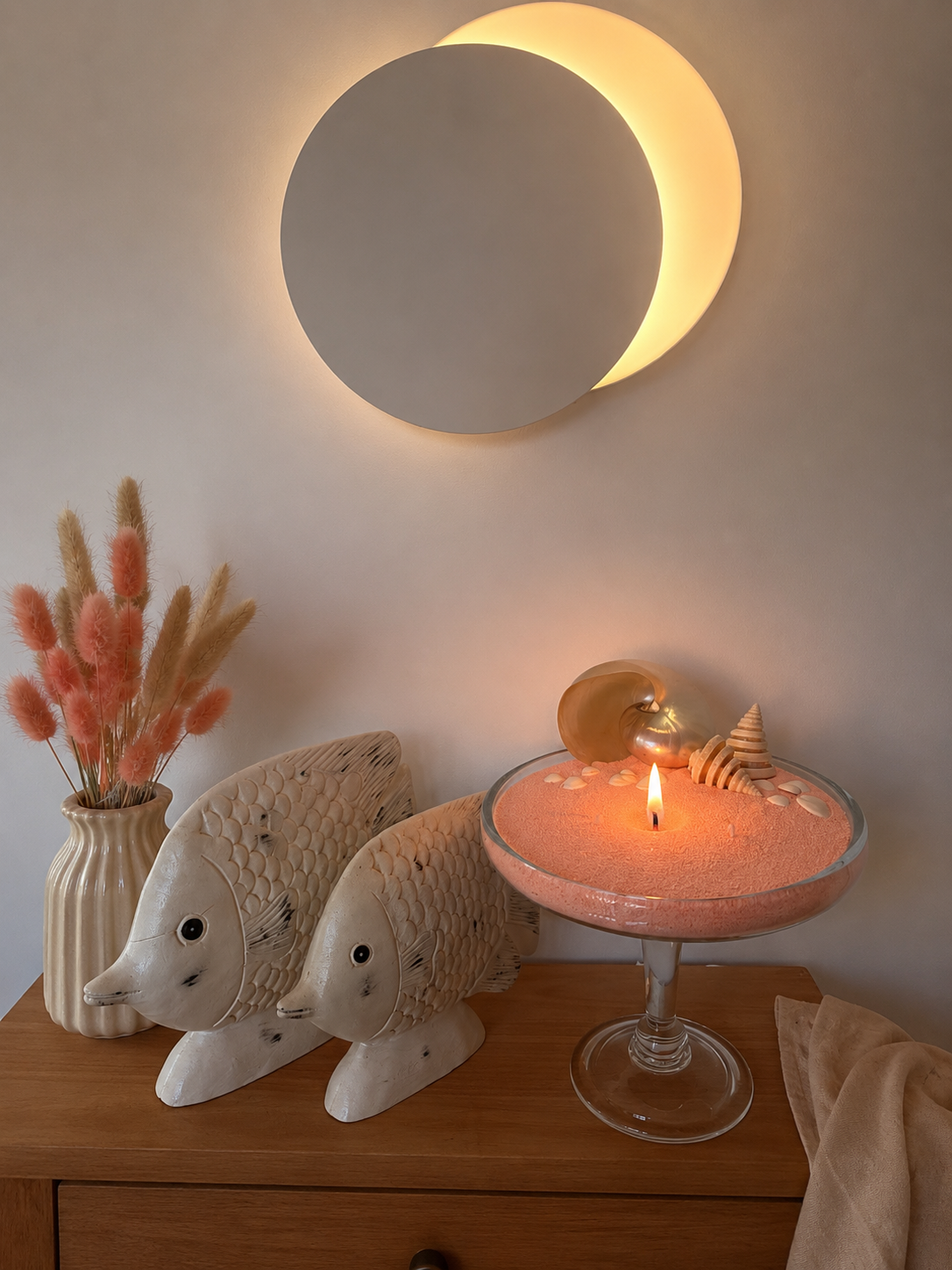 Bougie sablée rose Maison Charlee allumée dans une coupe en verre avec coquillages et décoration bord de mer élégante