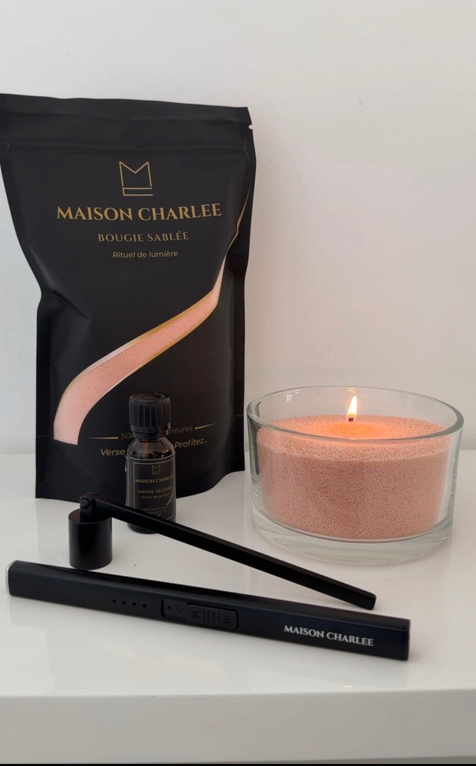 Bougie Rose sablé Maison Charlee allumée avec sable de bougie végétal, parfum de Grasse, briquet USB rechargeable et éteignoir.