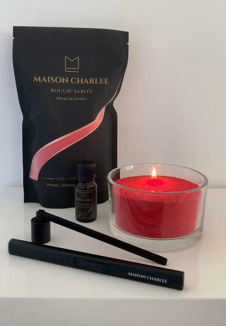 Bougie Rouge intense Maison Charlee allumée avec sable de cire végétale, parfum de Grasse, briquet USB et éteignoir.
