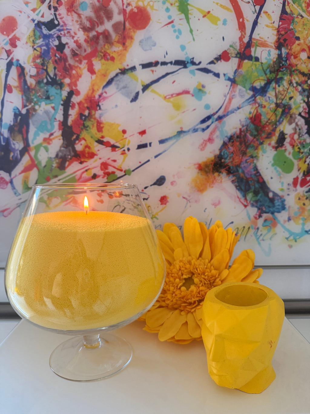 Bougie sablée Jaune Lumière Maison Charlee en perles de cire végétale dans un verre décoratif avec fleur jaune et décoration colorée.