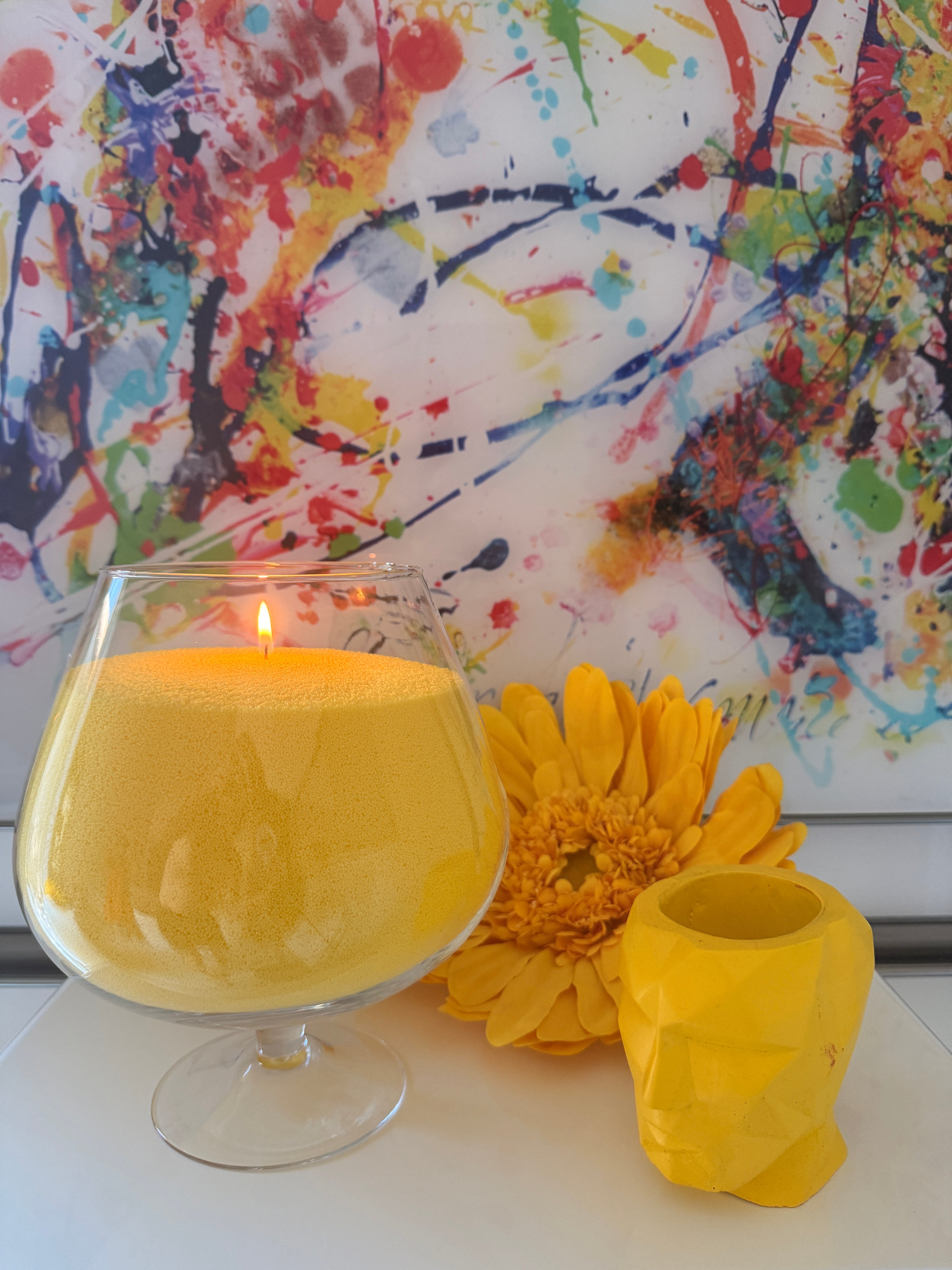 Bougie sablée Jaune Lumière Maison Charlee en perles de cire végétale dans un verre décoratif avec fleur jaune et décoration colorée.