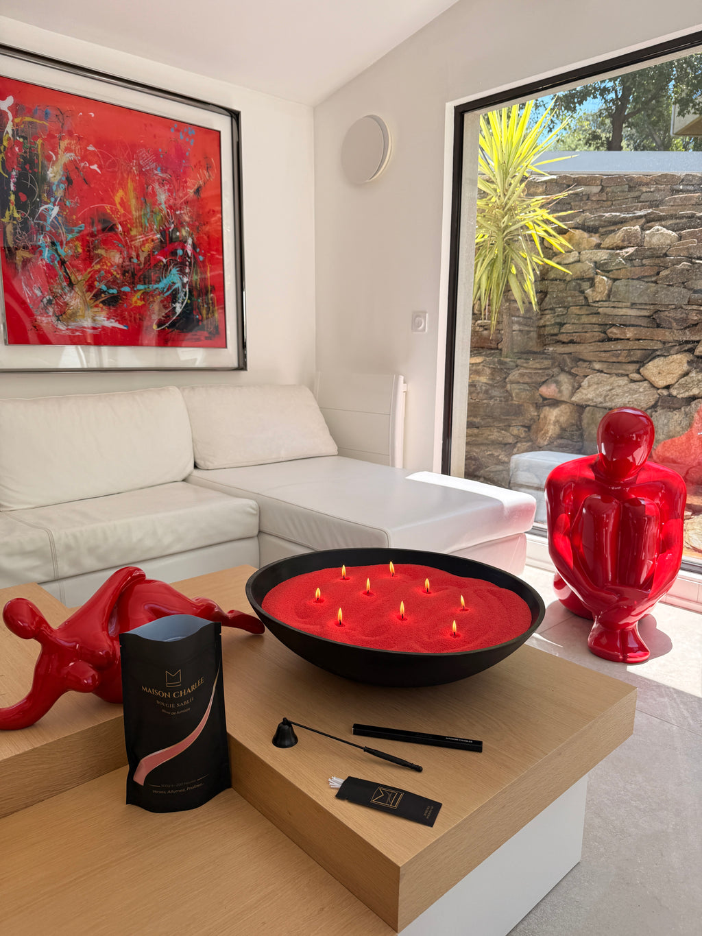 Bougie sablée Rouge Intense Maison Charlee présentée dans un grand plateau décoratif avec plusieurs flammes allumées.