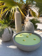 Bougie sablée Vert Sauge Maison Charlee dans une vasque décorative en extérieur, entourée de plantes méditerranéennes et de palmiers.